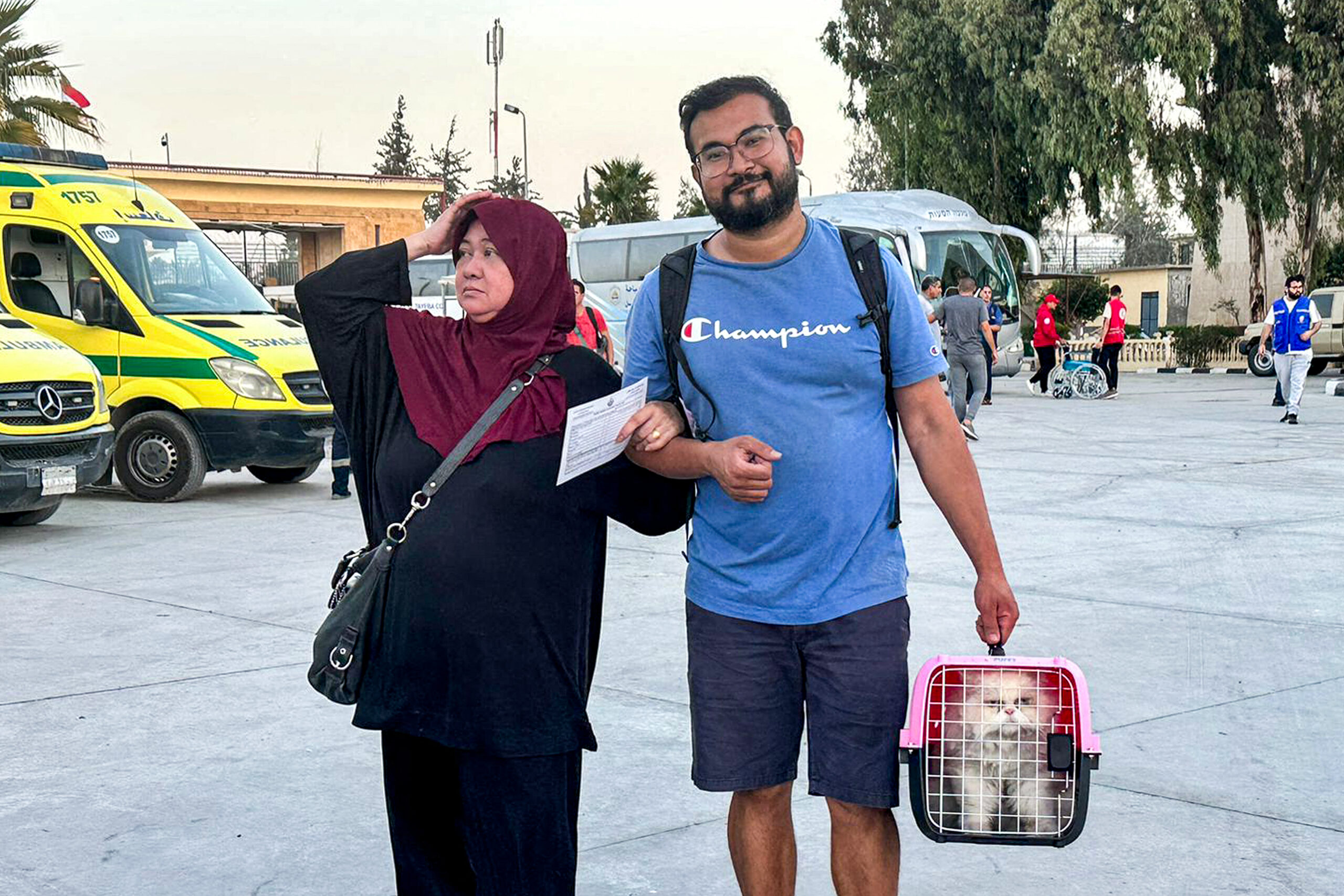 A couple of Filipino Palestinian dual nationals walk with a cat in a pet-carrier on the Egyptian side of the Rafah border crossing with the Gaza Strip on November 9, 2023, after having crossed from the Palestinian side to flee the ongoing fighting between Israel and the Palestinian group Hamas. (Photo by AFP)