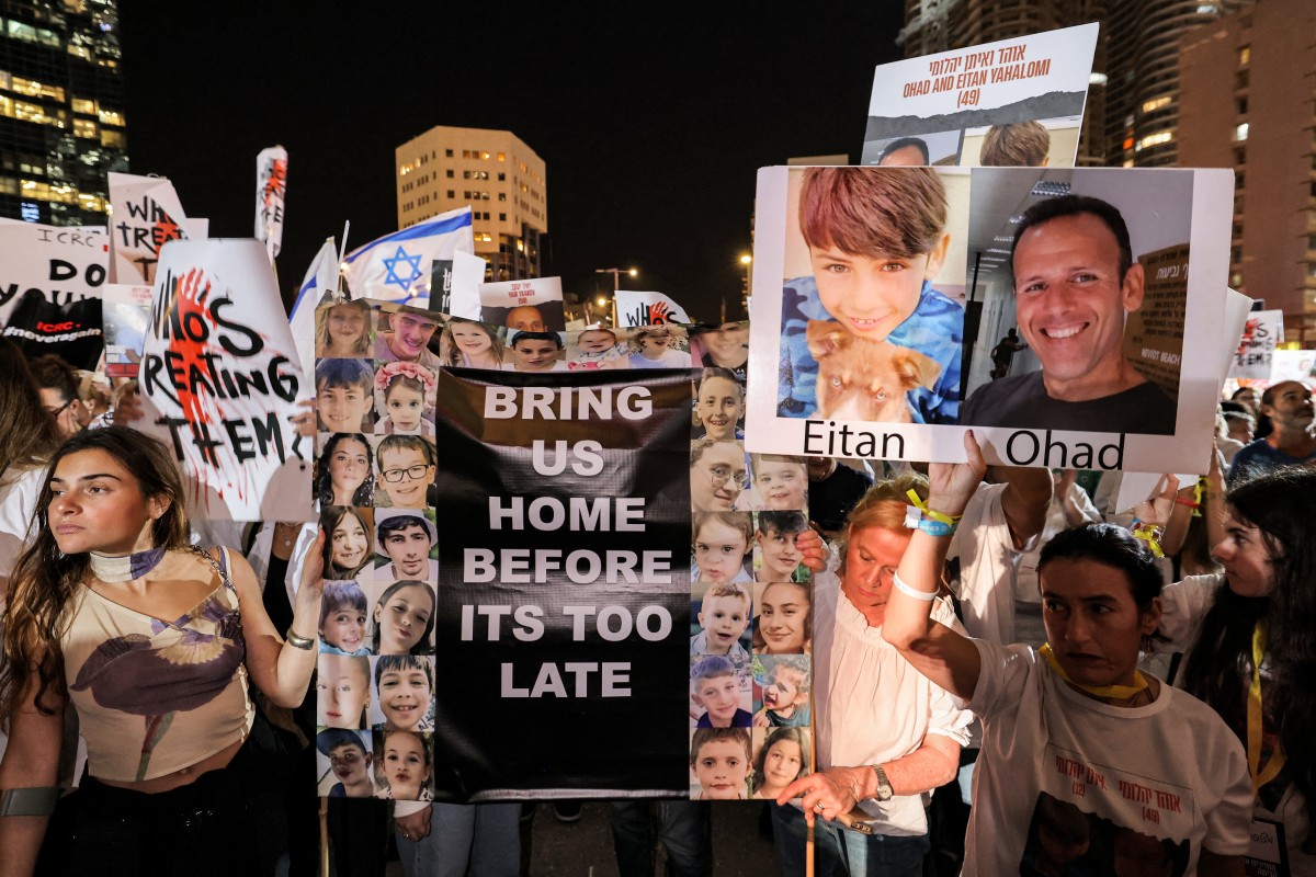 People gather with signs for a demonstration calling upon the International Committee of the Red Cross (ICRC) to take action for the release of hostages abducted by Palestinian militants on October 7 and currently held in the Gaza Strip, outside the ICRC offices in Tel Aviv on November 9, 2023 amid the ongoing fighting between Israel and the Palestinian group Hamas. (Photo by AHMAD GHARABLI / AFP)