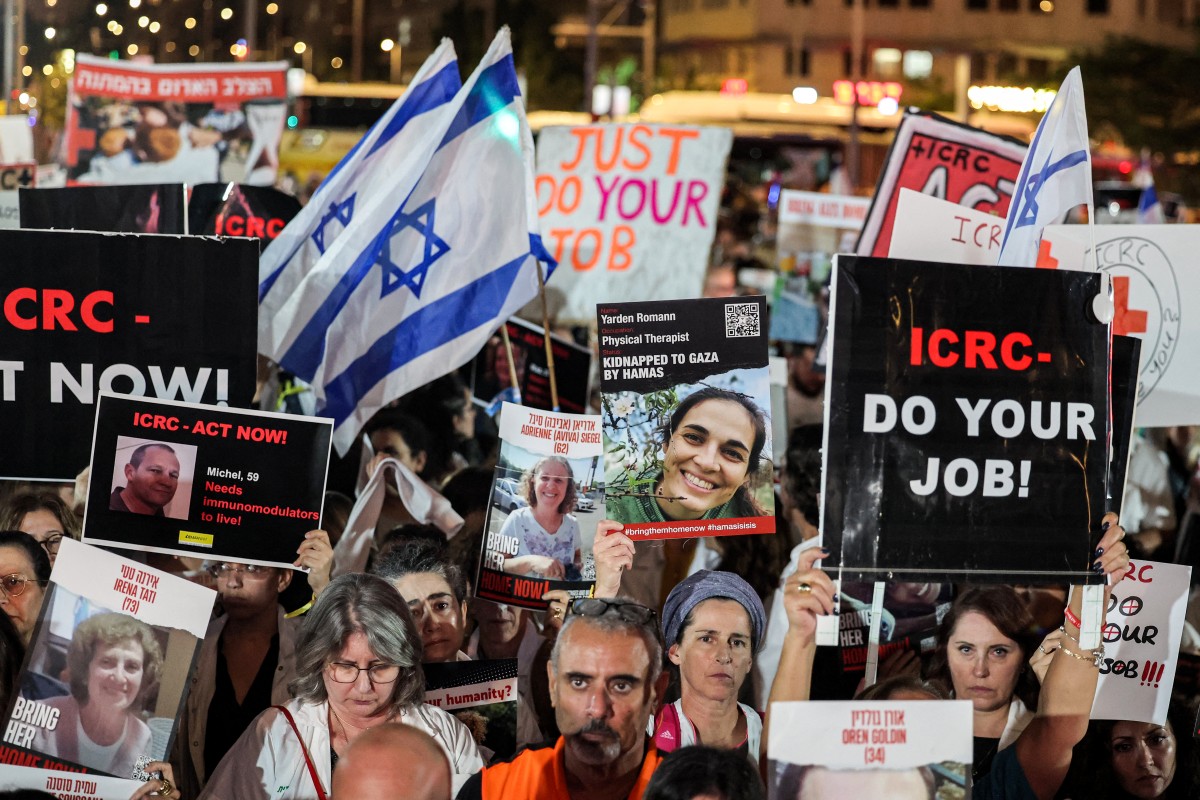 People gather with signs for a demonstration calling upon the International Committee of the Red Cross (ICRC) to take action for the release of hostages abducted by Palestinian militants on October 7 and currently held in the Gaza Strip, outside the ICRC offices in Tel Aviv on November 9, 2023 amid the ongoing fighting between Israel and the Palestinian group Hamas. (Photo by AHMAD GHARABLI / AFP)